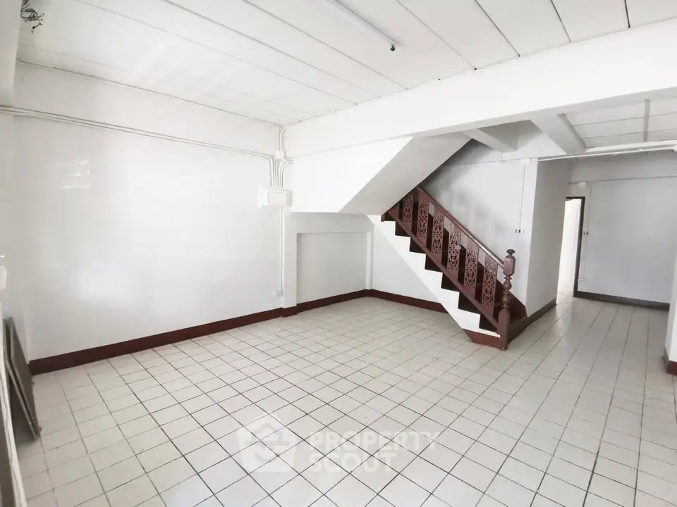 Spacious interior with tiled flooring and wooden staircase, ideal for customization.