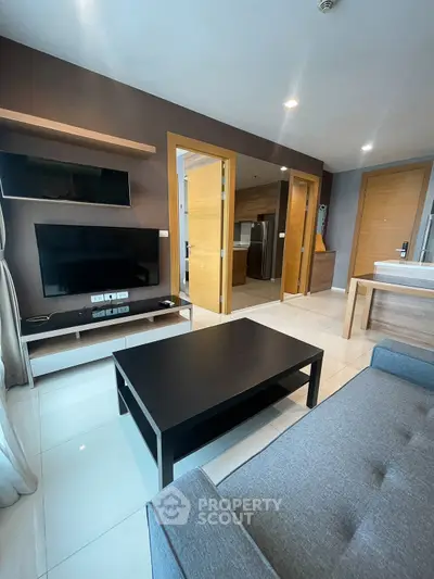 Modern living room with sleek furniture and open layout, featuring a flat-screen TV and stylish decor.