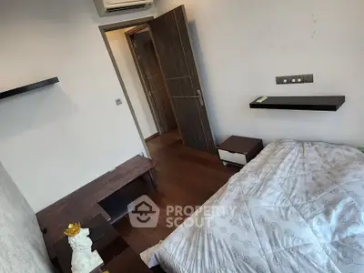 Cozy bedroom with modern decor and wooden flooring, featuring a minimalist design and air conditioning.