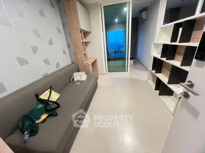 Modern apartment interior with stylish shelving and cozy seating area, featuring a view through glass doors.