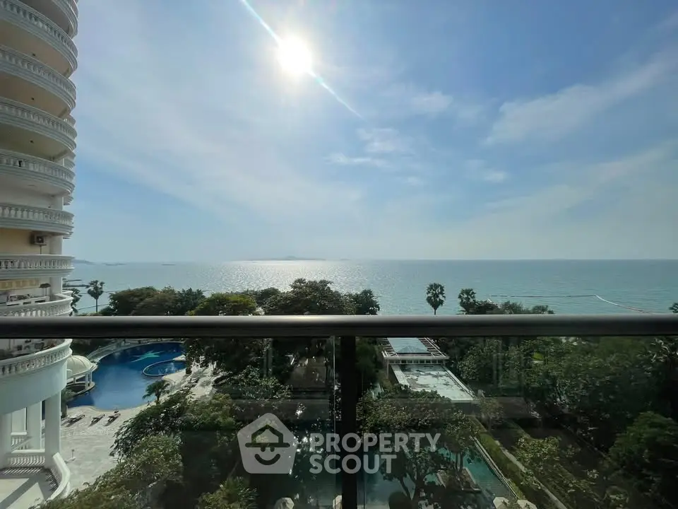Stunning ocean view from a high-rise balcony with pool and lush greenery below.