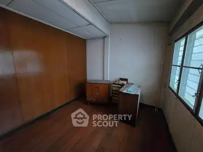 Cozy study room with wooden floors and ample natural light from large windows.