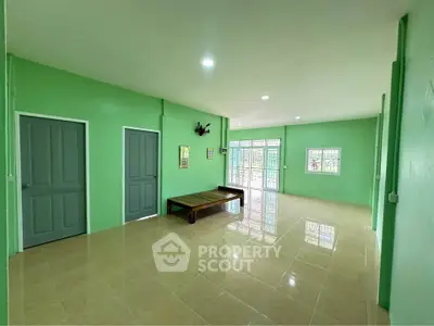 Spacious green-walled living room with tiled flooring and ample natural light.