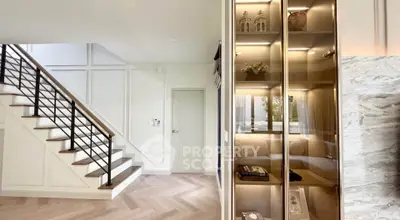Elegant modern interior with stylish staircase and glass display cabinet in a bright living space.