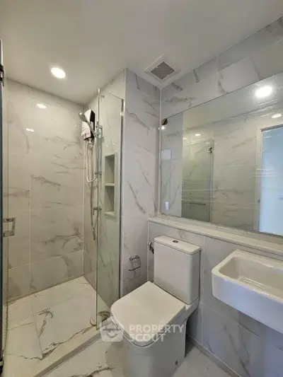 Modern bathroom with sleek design, featuring a glass shower enclosure and elegant marble tiles.