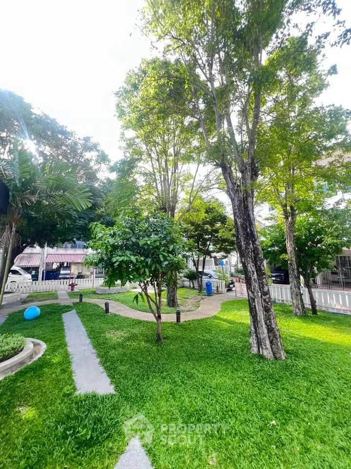 Lush green garden with trees and pathways in a serene residential area.