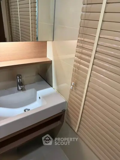 Modern bathroom with sleek sink and wooden blinds, perfect for a contemporary home.