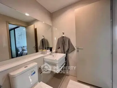 Modern bathroom with sleek fixtures and a glimpse of a cozy bedroom, showcasing contemporary design.