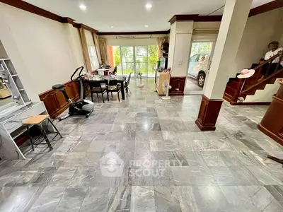 Spacious living room with elegant tile flooring and large windows offering natural light and garden view.