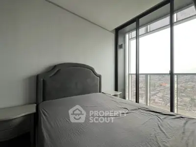 Modern bedroom with large windows offering stunning city views