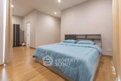 Spacious bedroom with modern decor and wooden flooring, featuring a comfortable bed and ample natural light.