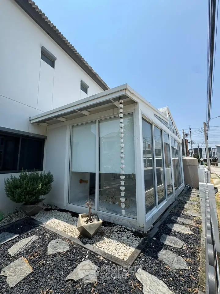 Modern white house with glass sunroom and landscaped garden path