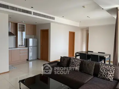 Modern open-plan living room with sleek kitchen and dining area, featuring contemporary furniture and neutral tones.