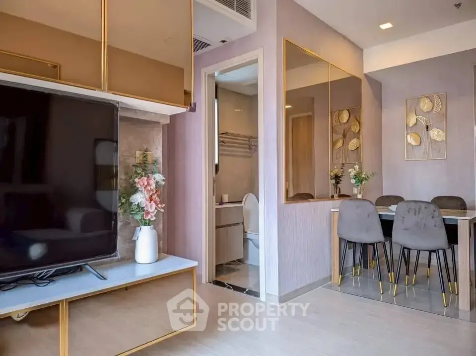 Modern living room with elegant dining area and large TV, featuring stylish decor and wall art.