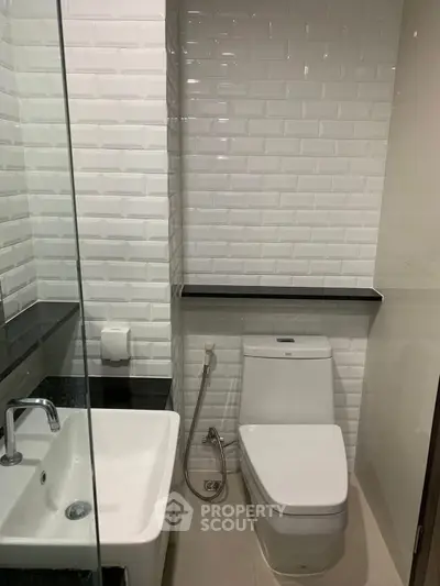 Modern bathroom with sleek white tiles and contemporary fixtures.