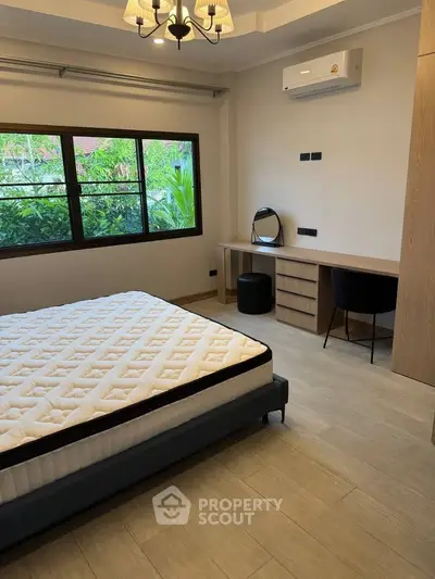Spacious bedroom with modern decor and large window overlooking greenery