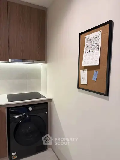 Modern kitchen corner with sleek cabinetry and built-in washing machine, ideal for compact living spaces.
