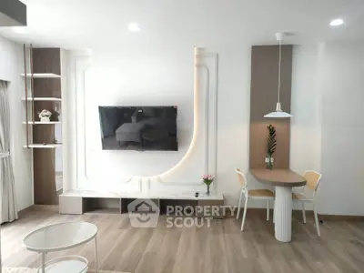 Modern living room with stylish TV setup and cozy dining area, featuring elegant decor and warm lighting.