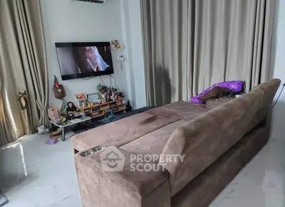 Cozy living room with plush sofa and wall-mounted TV, perfect for relaxation and entertainment.