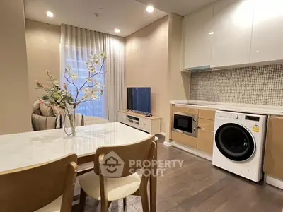 Modern open-layout living room with kitchen, featuring washing machine and stylish decor.