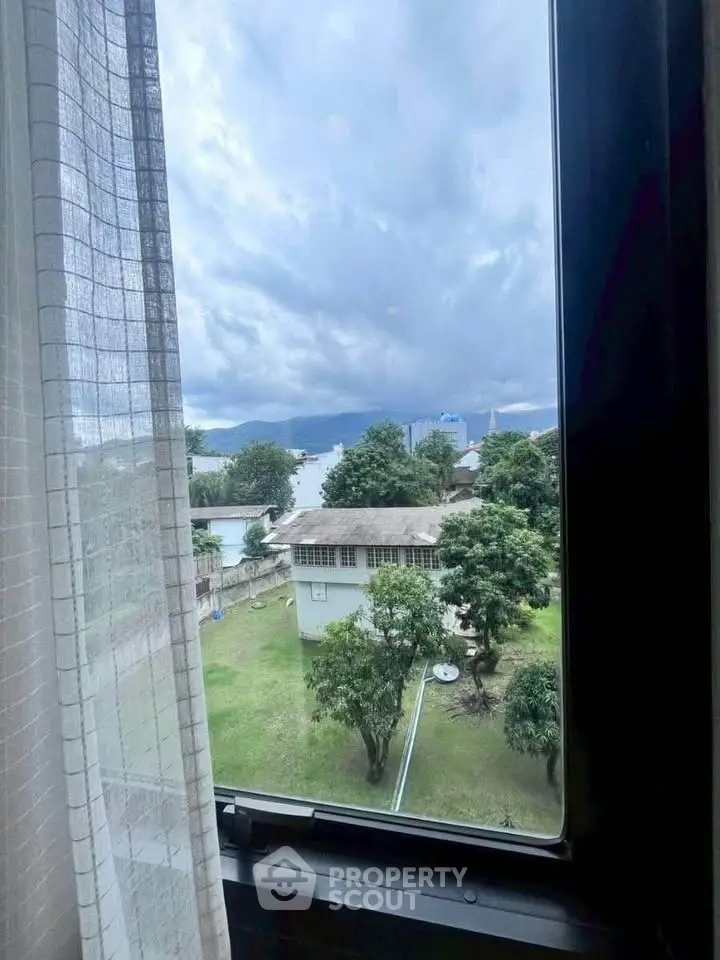 Scenic view from window overlooking lush garden and distant mountains, perfect for nature lovers.