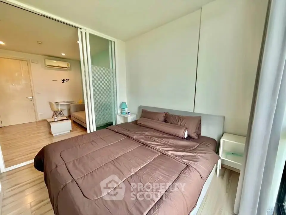Modern bedroom with cozy brown bedding and sliding glass doors in a stylish apartment.