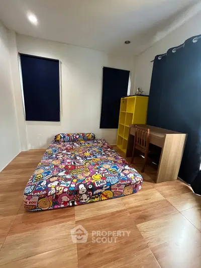 Cozy bedroom with colorful bedding, wooden flooring, and modern furniture, perfect for a vibrant living space.