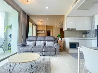 Modern living room with plush sofa, open kitchen, and balcony access in a stylish apartment.