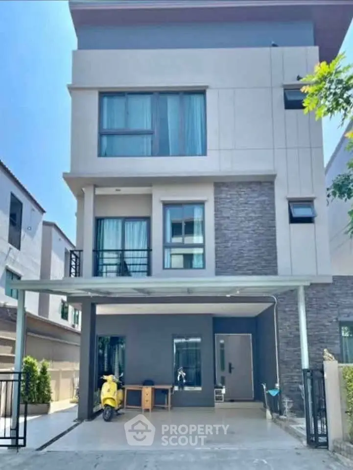 Modern three-story townhouse with spacious driveway and sleek exterior design.