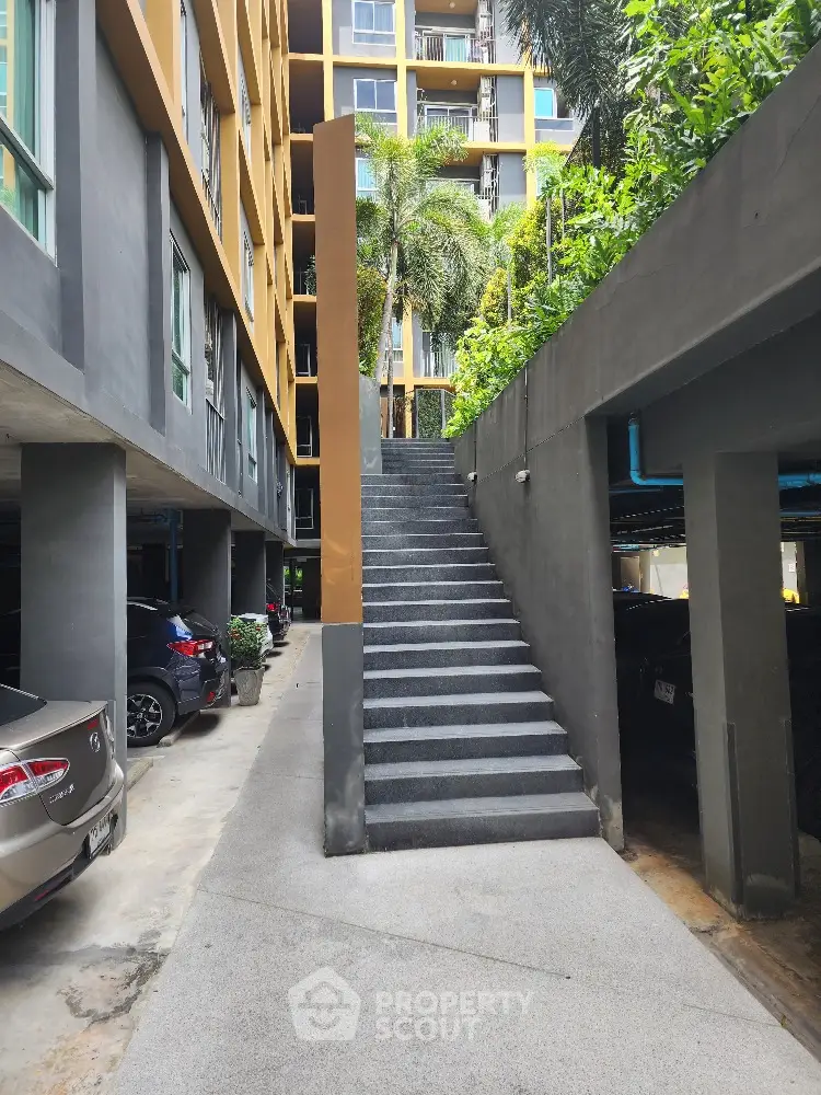 Secure parking area in a modern residential building with easy access stairs leading to a welcoming, lush green environment.