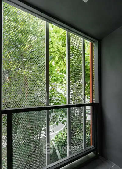 Modern balcony with stylish metal mesh railing and lush greenery view.