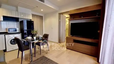 Modern living room with dining area, TV, and kitchen appliances in a stylish apartment.