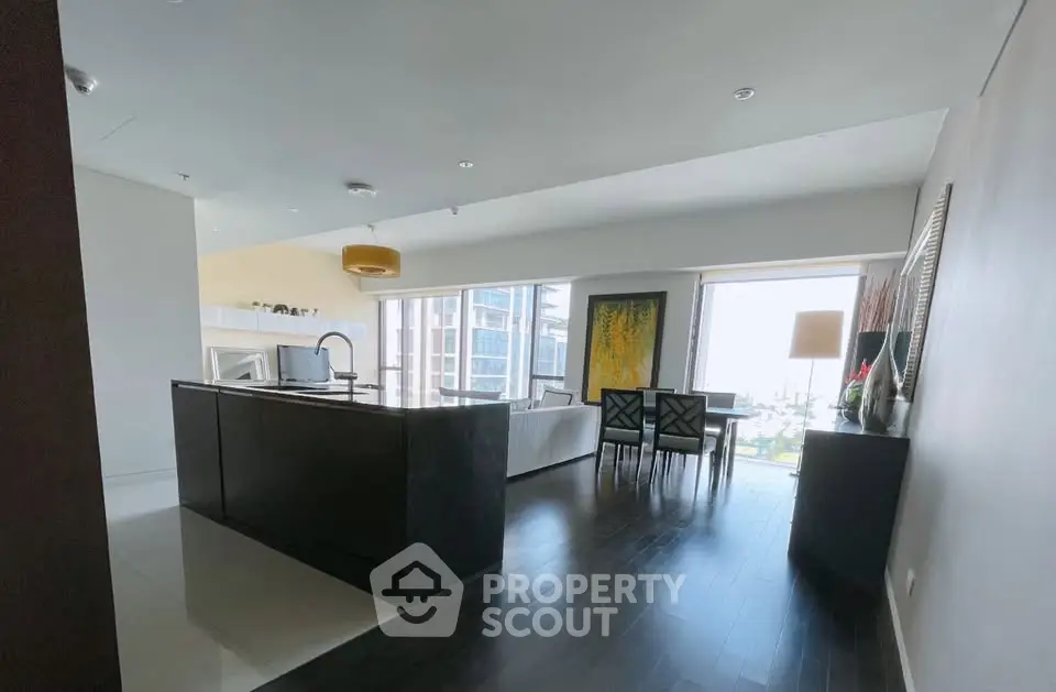 Spacious modern living room with open kitchen and stunning city view, perfect for urban living.