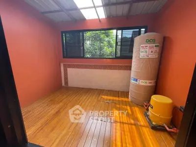Bright room with wooden flooring and large water tank, ideal for storage or utility use.