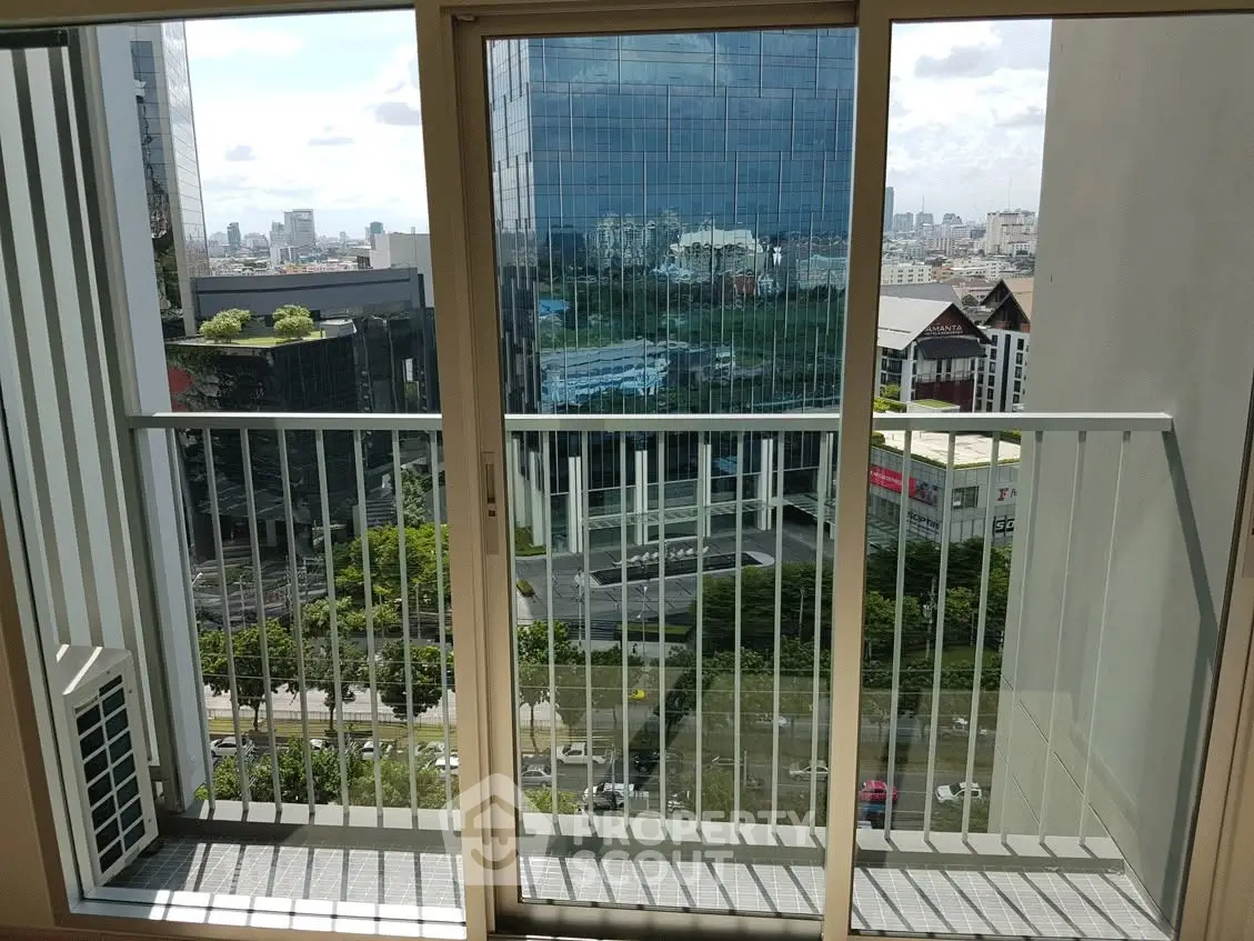 Modern high-rise apartment balcony with cityscape view and glass railing.