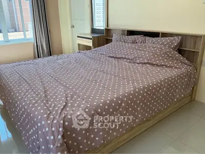 Cozy bedroom with polka dot bedding and ample natural light from large window.