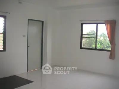 Bright and airy unfurnished bedroom with a large window offering a lush green view, perfect canvas for personalization.