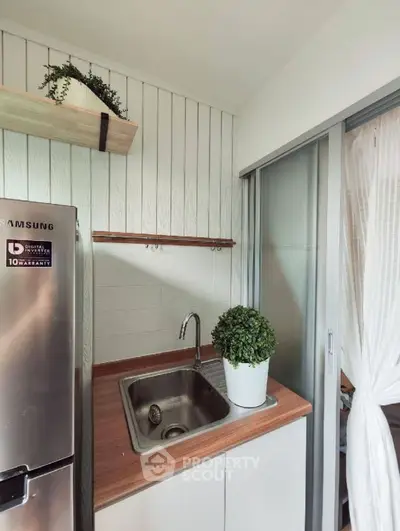 Modern compact kitchen with stainless steel fridge and wooden countertop