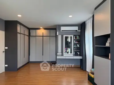 Spacious modern bedroom with sleek built-in storage and elegant wood flooring.