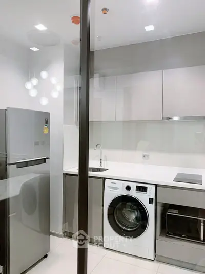 Modern kitchen with sleek appliances and washer-dryer combo in a compact layout.