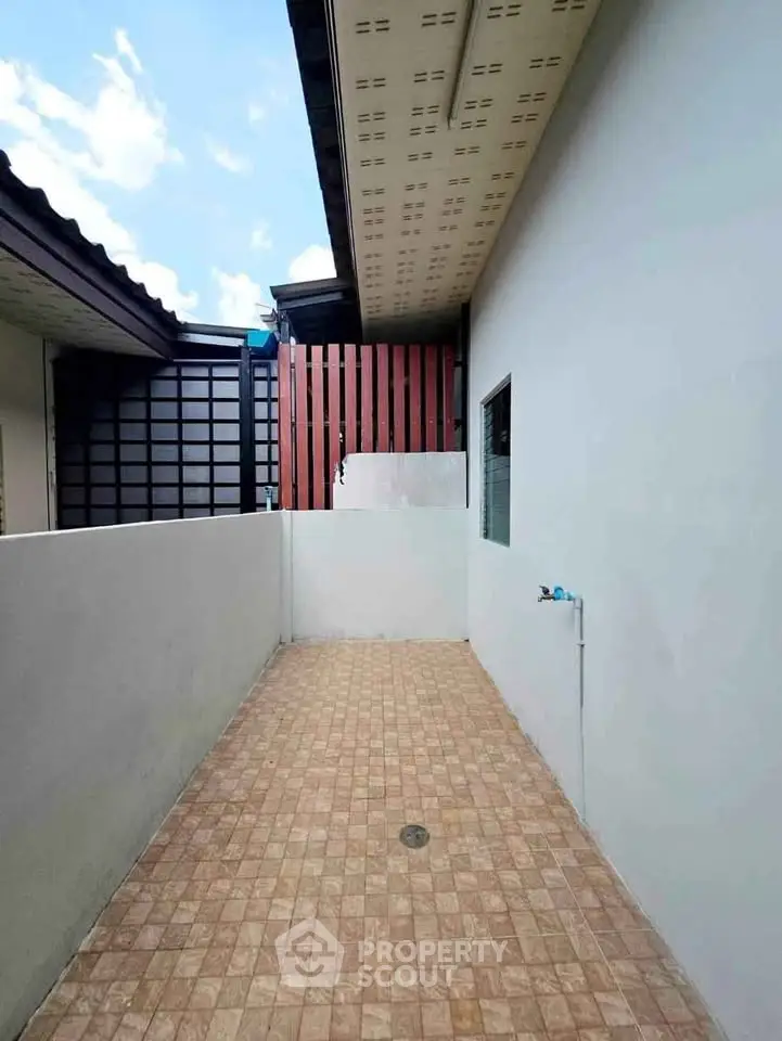 Spacious outdoor patio with tiled flooring and privacy walls, perfect for relaxation.