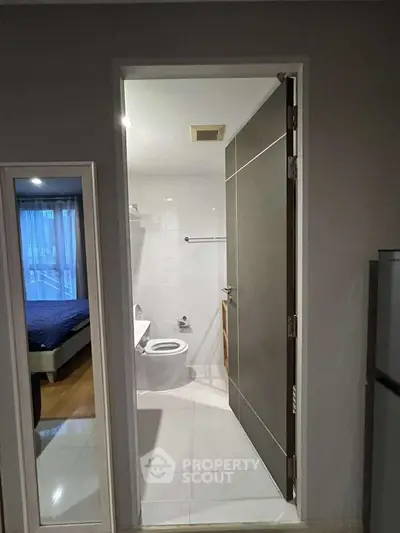 Modern apartment bathroom with sleek design and adjacent bedroom view