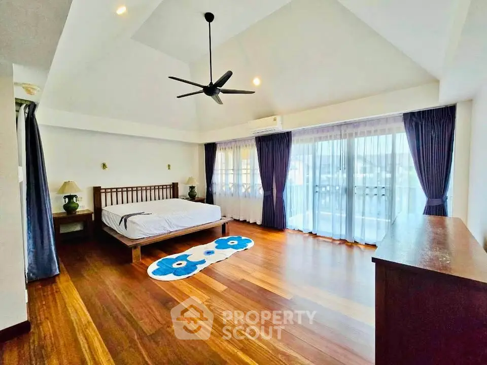 Spacious bedroom with wooden flooring and large windows in modern home