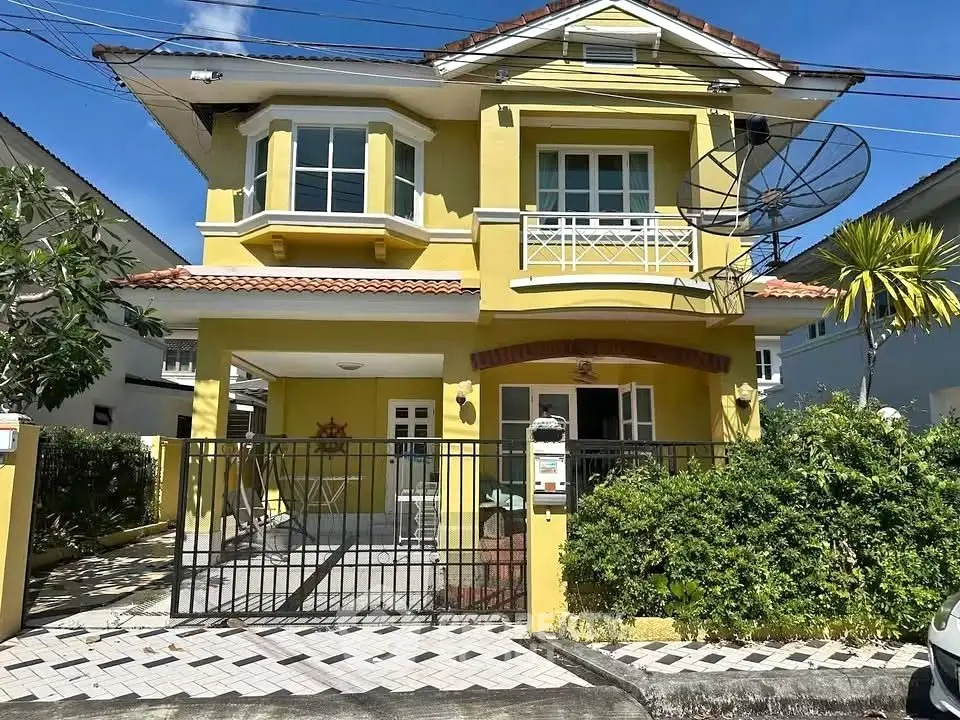 Charming yellow two-story house with satellite dish and gated driveway in sunny neighborhood.