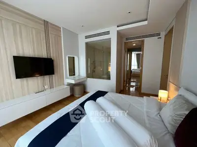 Luxurious modern bedroom with elegant decor and spacious layout, featuring a wall-mounted TV and stylish lighting.