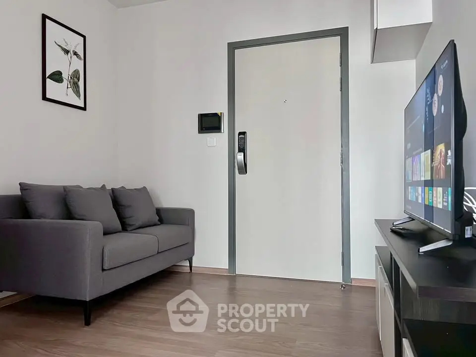 Modern living room with sleek gray sofa and wall-mounted TV, perfect for cozy relaxation.