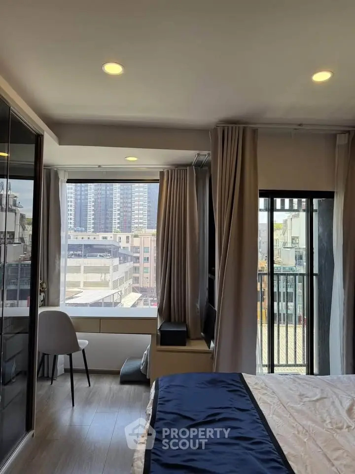 Modern bedroom with city view and balcony access, featuring elegant decor and ample natural light.