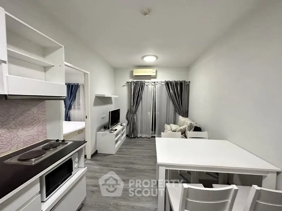 Modern living room with open kitchen, featuring sleek white furniture and stylish decor.