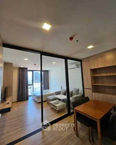 Modern apartment interior with glass partition, wooden flooring, and stylish furniture.