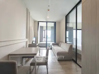 Modern apartment interior with open living and dining area, featuring sleek furniture and large windows.